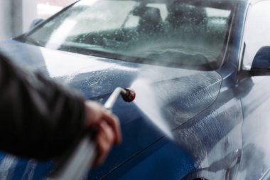 Man washing his car in car wash self service shop. Car maintenance concept