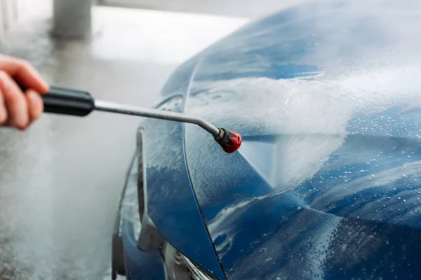 Man washing his car in car wash self service shop. Car maintenance concept