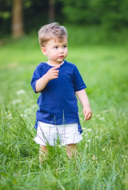 Mavi tişörtlü şirin sarışın çocuk güzel mavi gözlü bir şeye bakıyor.