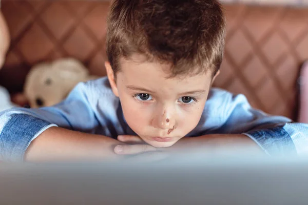 Ragazzo biondo carino attentamente guardando lo schermo del computer portatile. Bambini e tecnologia — Foto Stock