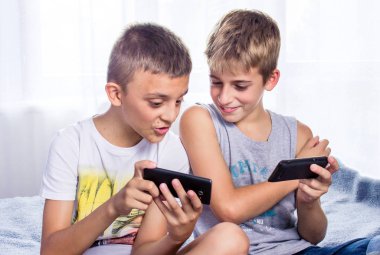 Çocuklar, kardeşler akıllı telefonlarıyla online oyun oynuyorlar. Modern çocuk etkinliği
