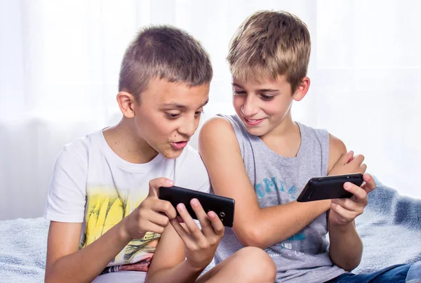 Çocuklar, kardeşler akıllı telefonlarıyla online oyun oynuyorlar. Modern çocuk etkinliği