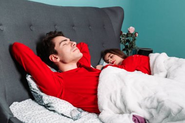 Kırmızı pijamalı tatlı bir çift yatakta uzanıyor, uyuyor, dinleniyor..