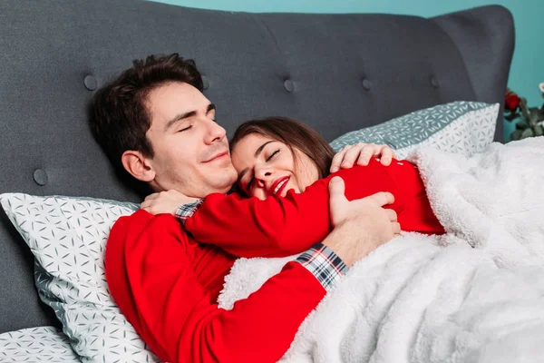 Casal deitado na cama abraçando e parecendo feliz. Conceito de dia dos namorados — Fotografia de Stock