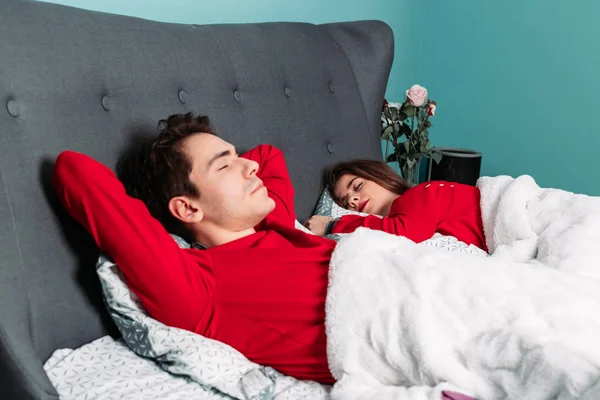 Bonito casal de pijama vermelho deitado na cama juntos, dormindo, relaxante . — Fotografia de Stock