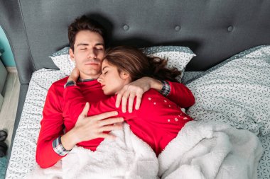 Çift yatakta yatıyor, sarılıyor ve mutlu görünüyor. Birlikte yatıyorlar..