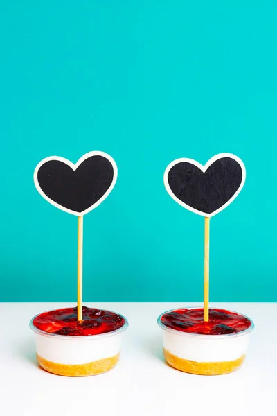 Δύο κέικ τυριού με μαύρη ξύλινη καρδιά κολλάνε μέσα τους. Ημέρα του Αγίου Βαλεντίνου έννοια. — Φωτογραφία Αρχείου