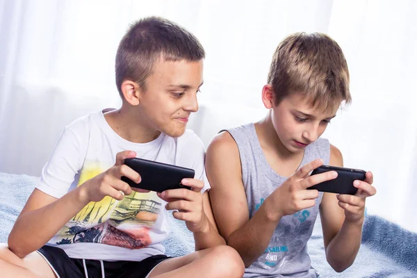 Niños pequeños, hermanos jugando en sus teléfonos inteligentes. Adicción a Internet — Foto de Stock