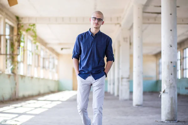 Cute, young man in blue shirt and white pants with eyeglasses. Teen fashion