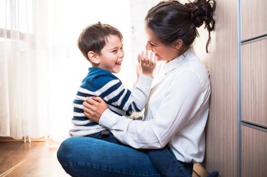 Mom and her son, sitting on the floor being affectionate with each other.