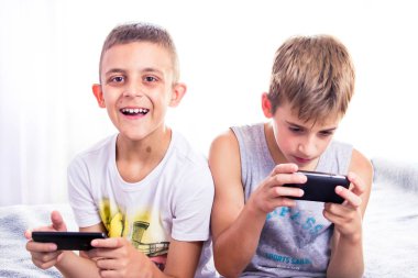 Çocuklar, kardeşler akıllı telefonlarıyla online oyun oynuyorlar. Modern çocuk etkinliği