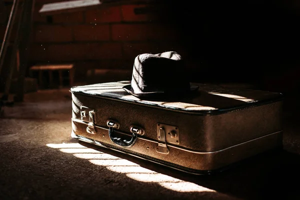 Старый ретро-чемодан с черной шляпой и черным фоном. Концепция путешествия — стоковое фото