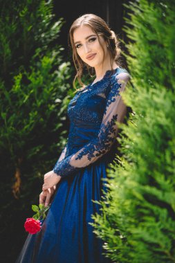 Elinde gül tutan göz kamaştırıcı ultramarinalı elbiseli güzel bir kız. Baloya hazırım..
