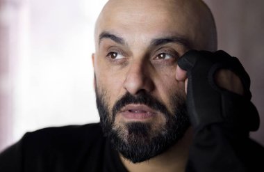 Spor eldiveni takan sakallı kel adam bir şey düşünüyor.