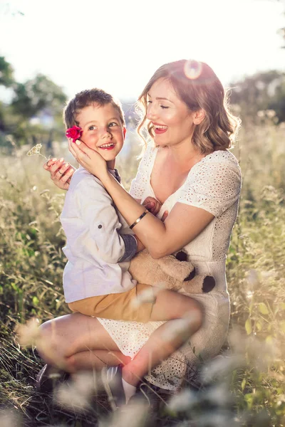 Boy with his beautiful mom. She is putting rose behind his ear. Mothers day — Stock Photo, Image