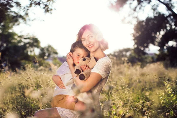 Mom holding her blond son in her arms. Outdoor photo. Mothers day — Stock Photo, Image