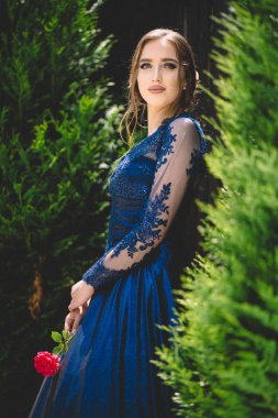 Elinde gül tutan göz kamaştırıcı ultramarinalı elbiseli güzel bir kız. Baloya hazırım..