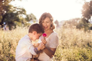 Boy with his beautiful mom. He gave her flower and they laugh. Mothers day