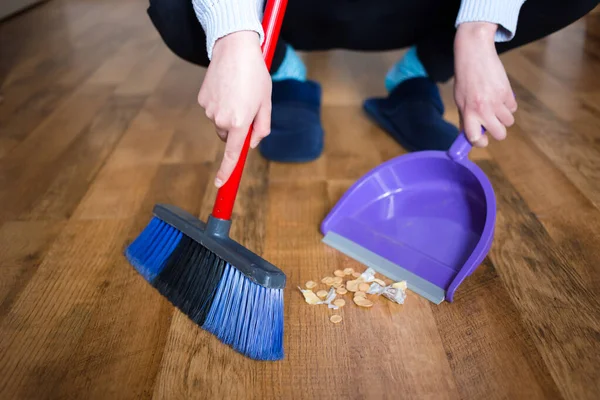 Mujer en zapatillas azules usando escoba interior para la limpieza del suelo, recogiendo la suciedad . — Foto de Stock