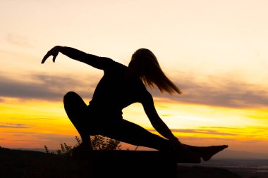 Gün batımında siluet kadın koç yoga uygulaması. Yoga konsepti