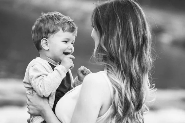 Jovem Mãe Segurando Seu Lindo Filho Loiro Olhando Para Ele — Fotografia de Stock