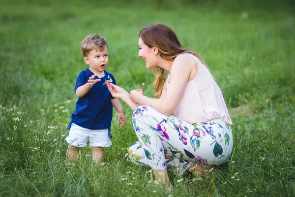 若いお母さんは彼女の美しい金髪の息子に花をあげます 親子関係 母の日 — ストック写真