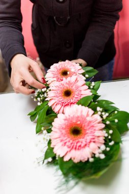Çiçekçi kadın tarafından çiçekçide Gerbera papatya buketi hazırlanıyor.