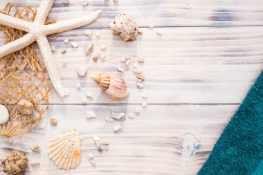 Beyaz ahşap arka planda deniz kabukları olan denizyıldızı. Yaz saati, tatil konsepti, mavi havlu ile hediyelik eşya
