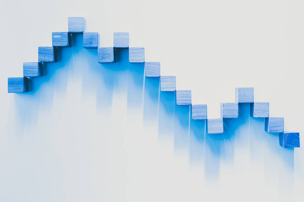 Declining blue graphic curve made with wooden boxes. Financial concept