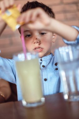 Tatlı, sarışın çocuk alkolsüz içecek yapıyor. Çocuk içecekleri.