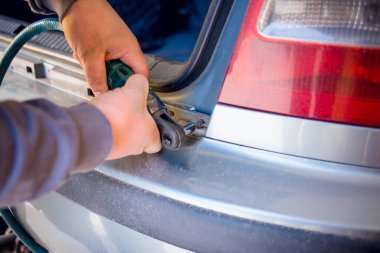 Otomatik tornavida ile arabanın arkasını tamir eden araba tamircisinin fotoğrafı. Ulaşım sorunları, araba tamir konsepti