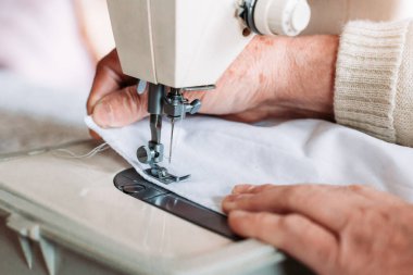 Kadınların el yapımı mashine tıbbi maskesini dikerken yakın plan çekimleri. Tıbbi ekipman sıkıntısı
