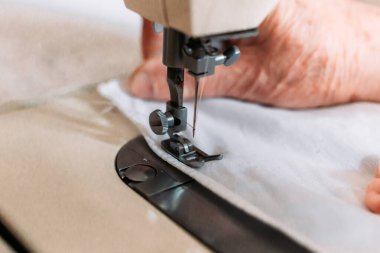 Kadınların el yapımı mashine tıbbi maskesini dikerken yakın plan çekimleri. Tıbbi ekipman sıkıntısı
