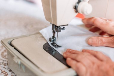 Kadınların el yapımı mashine tıbbi maskesini dikerken yakın plan çekimleri. Tıbbi ekipman sıkıntısı
