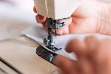 Kadınların el yapımı mashine tıbbi maskesini dikerken yakın plan çekimleri. Tıbbi ekipman sıkıntısı