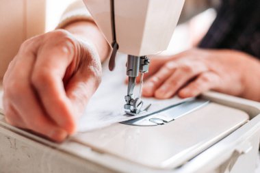 Kadınların el yapımı mashine tıbbi maskesini dikerken yakın plan çekimleri. Tıbbi ekipman sıkıntısı