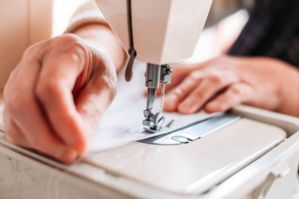 Крупным планом женщины вручную шьют на машинке домашнюю медицинскую маску. Нехватка медицинского оборудования
