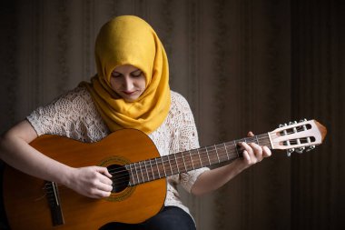 Gitar çalan sevimli, modern Müslüman kadın portresi. Çeşitlilik kavramı
