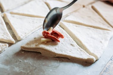 Kadın eli, kruvasan rulosuna kaşık doldurmayı da ekliyor. Kruvasan rulosu yapma süreci