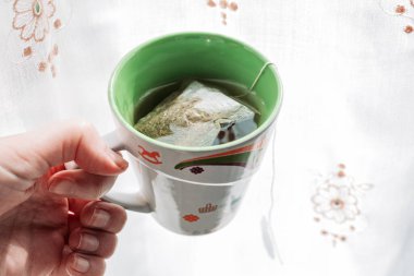 Sabahları elinde çay fincanı, pencerenin yanında.