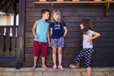 Çocuklar dedikodu yapıyor. Oğlan bir kıza bir şeyler fısıldıyor, diğer kız da gizlice dinliyor. Çocuklar oynuyor, oyun oynuyor..