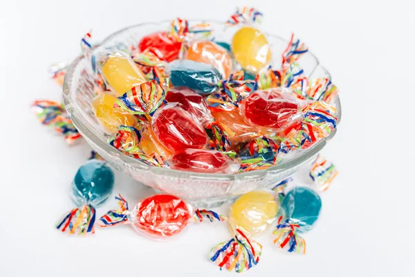 Beyaz arkaplanda izole edilmiş sert paketlenmiş şekerlemelerle dolu bir kâse.