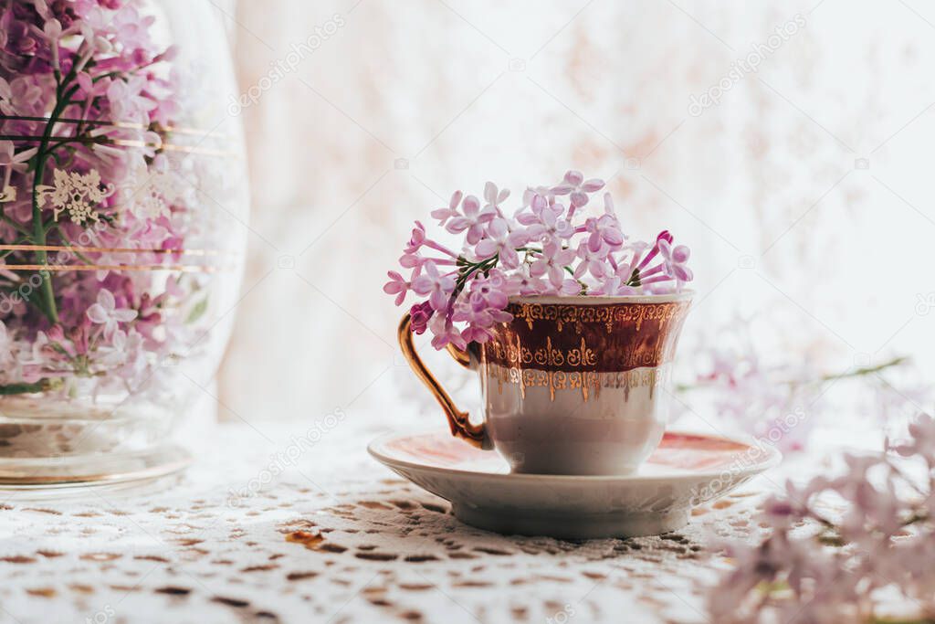 Retro tea cup with lilac flowers in it. Home decoration. Springtime vibes. Space for text