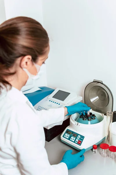 Laboratuvar teknisyeni numune tüplerini laboratuvar santrifüjüne koyuyor. Corona virüs araştırması