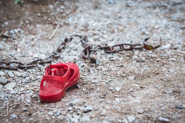 Kırmızı çocuk sandaleti zincirle kumda yatıyor. Kaybolanların Uluslararası Günü konsepti