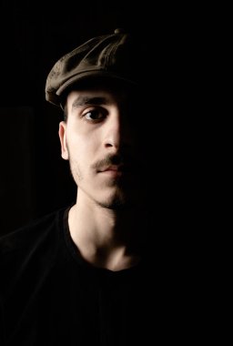 Bıyıklı, siyah şapkalı, esmer, yakışıklı bir gencin portresi..