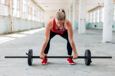 Formda sarışın kadın ağırlığı kırmızı spor kıyafetlerle kaldırıyor. Eğitim, aktif yaşam tarzı.