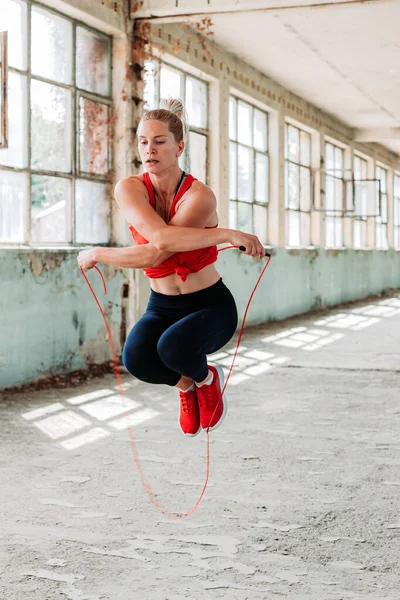 Athletic fit girl rope jumping. Fitness training, healthy lifestyle. Doing figure 8. Indoors shot in an old building