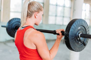 Formda sarışın kadın ağırlığı kırmızı spor kıyafetlerle kaldırıyor. Eğitim, aktif yaşam tarzı. Kol egzersizi. Arka plan
