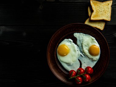 Çırpılmış yumurta, taze domates ve arka planda iki dilim ekmek..